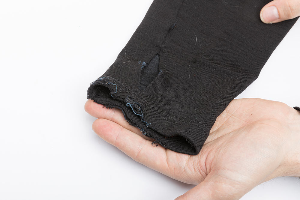 A frayed cuff of a long sleeve shirt held on flat of the hand.