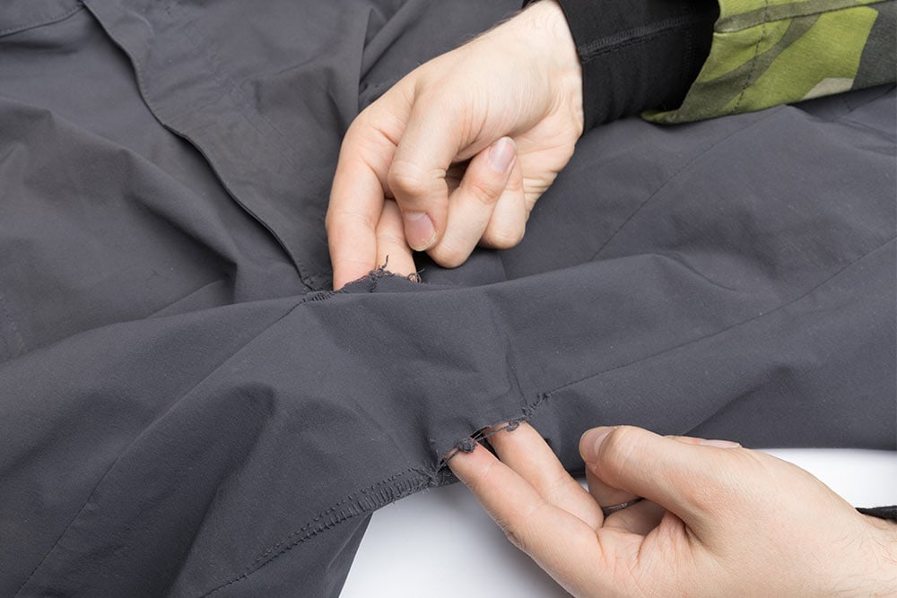 Two crotch seams of pants that are broken. Two fingers have been inserted into both seams.