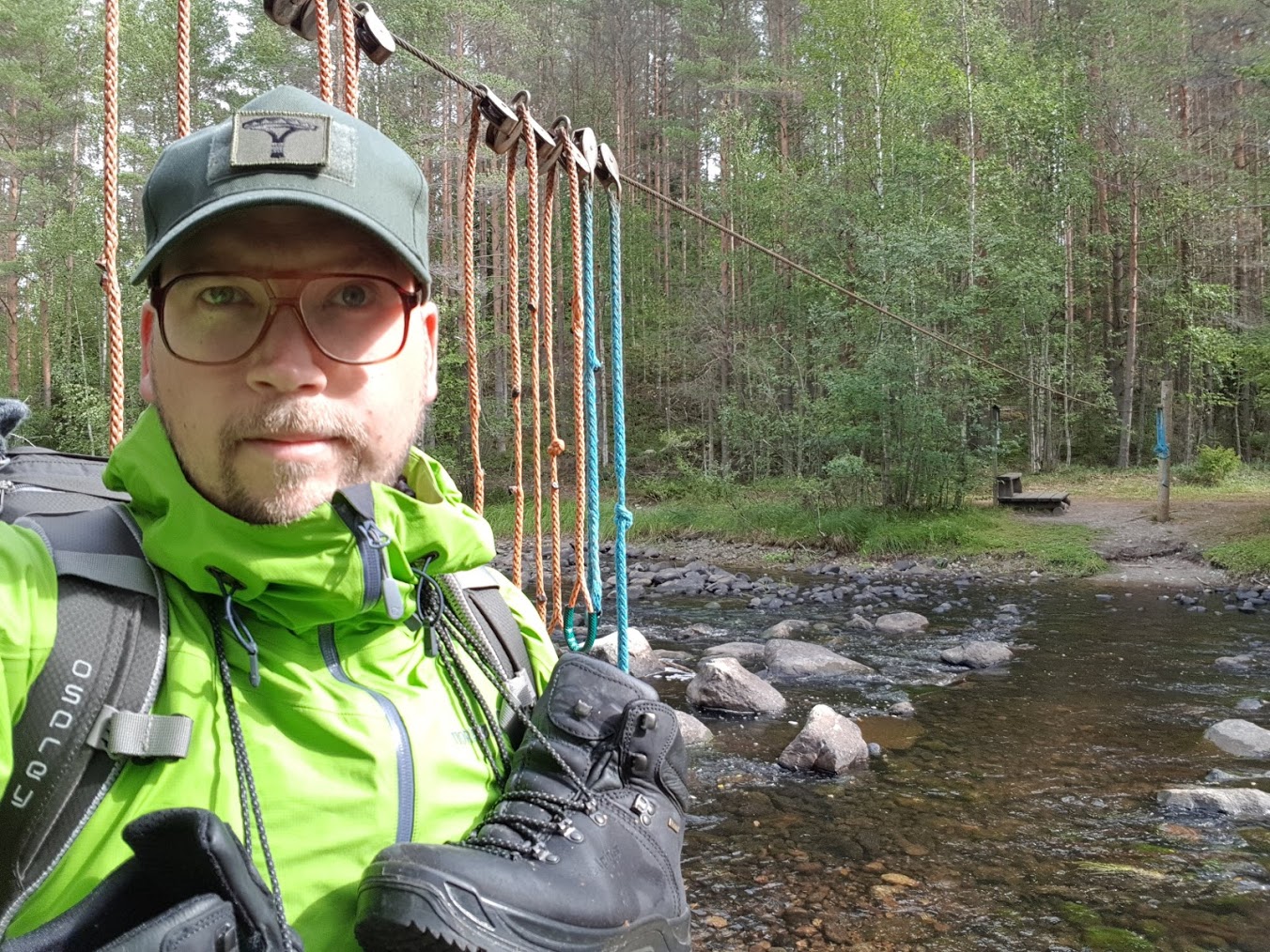 Vaealtaja joen ylityspaikalla kengät niskassa roikkumassa.