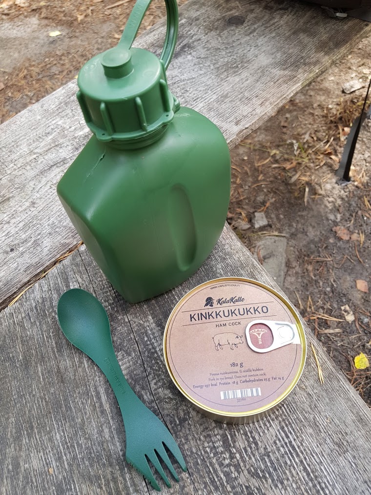A plastic green army style water canteen, a spork and a can of Kinkkukukko.