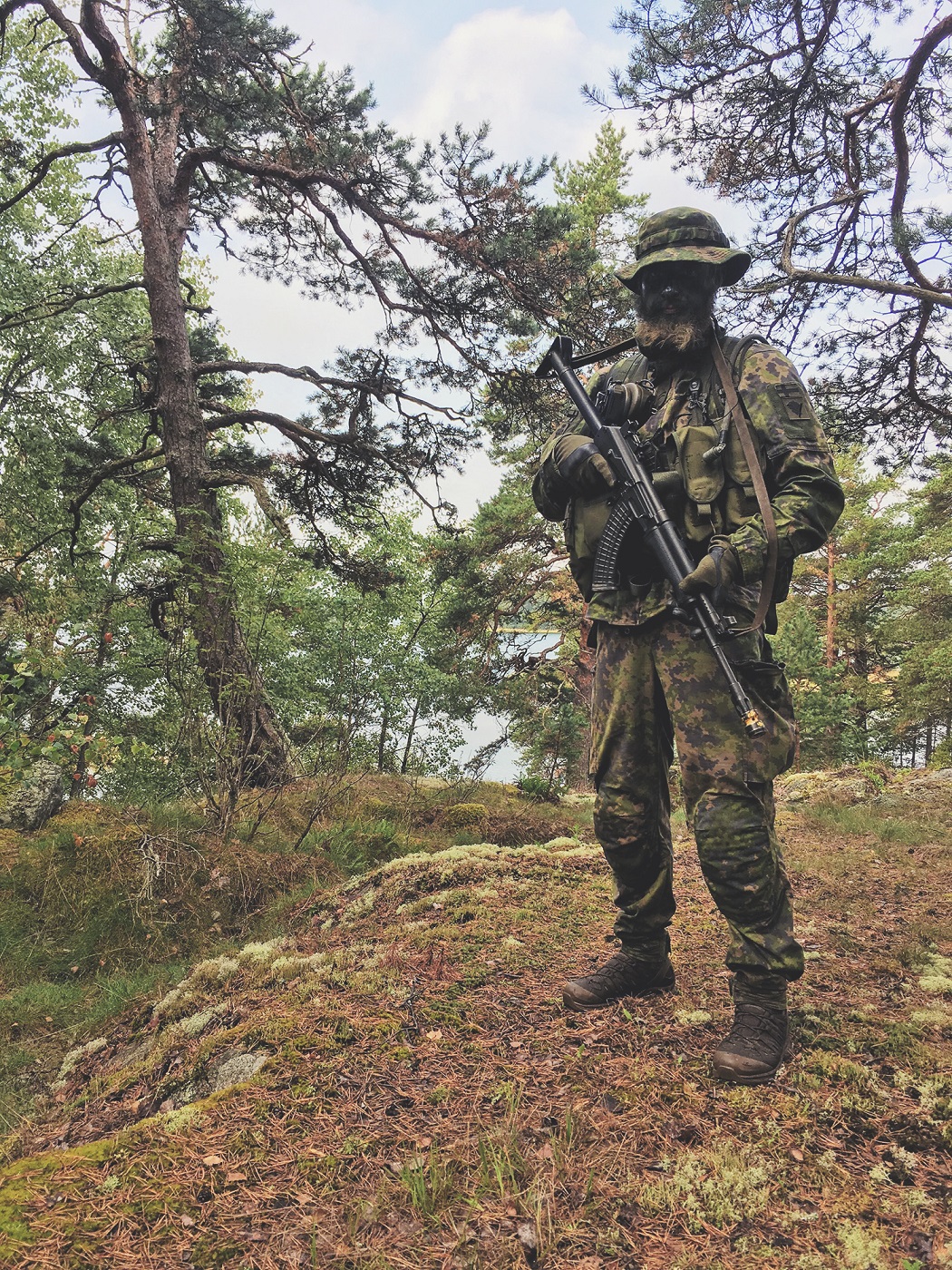 A soldier wearing camouflage clothing in the woods.