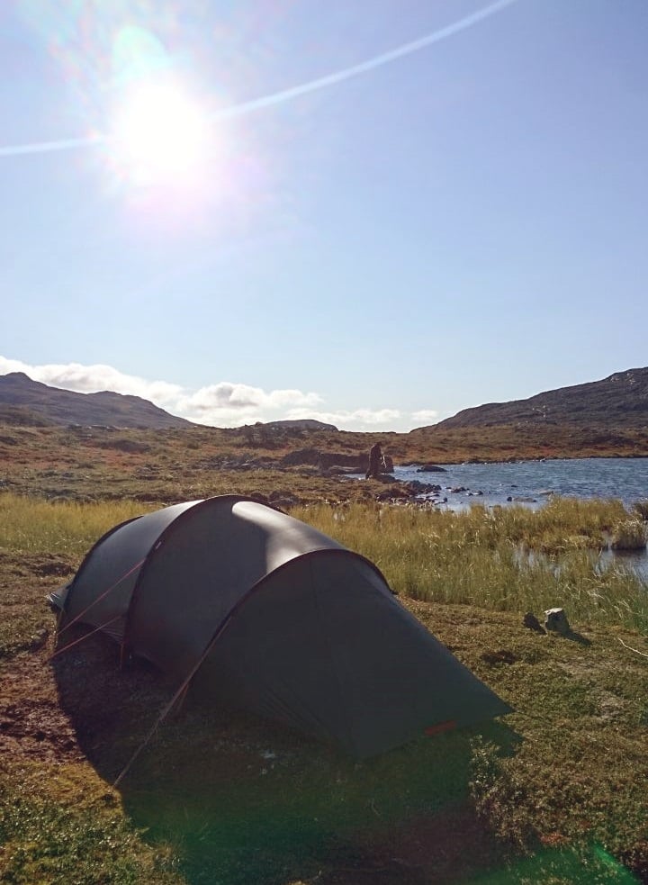 A sunny camping spot next to water.