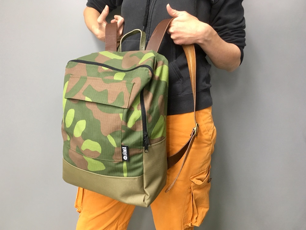 A camo backpack with leather shoulder straps.