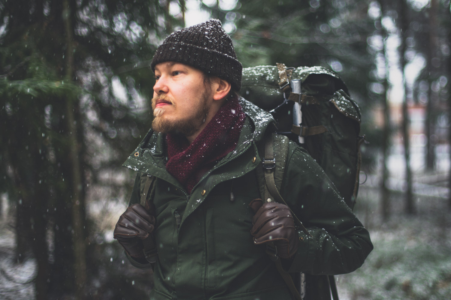 A man in the woods with some snow and in hiking gear.