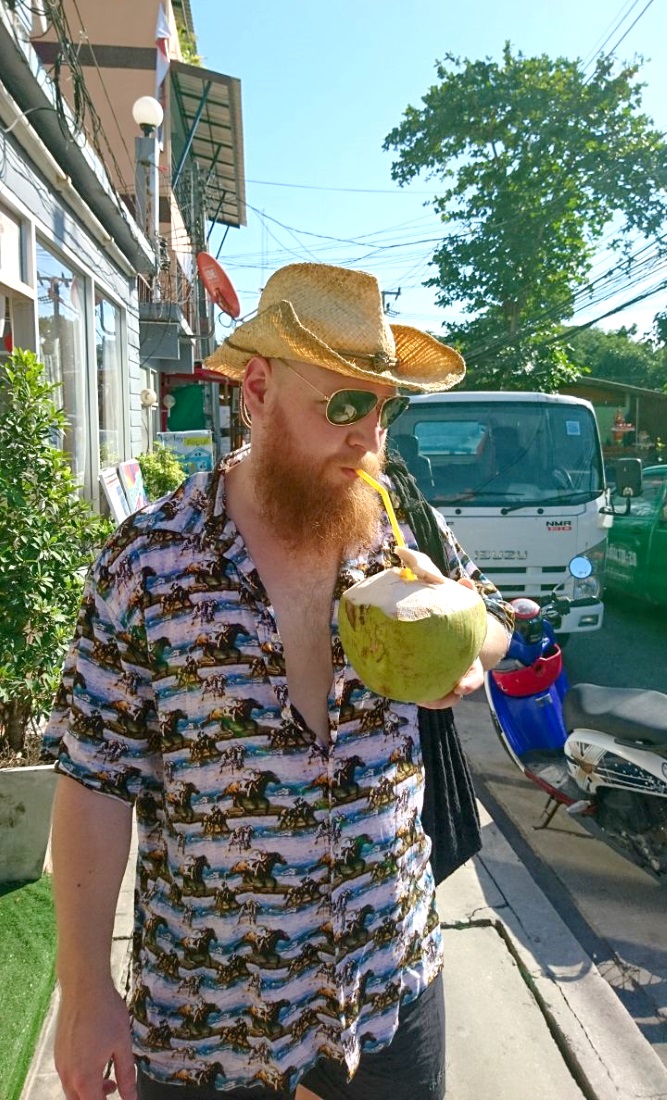 A man drinking from a coconut with a straw.