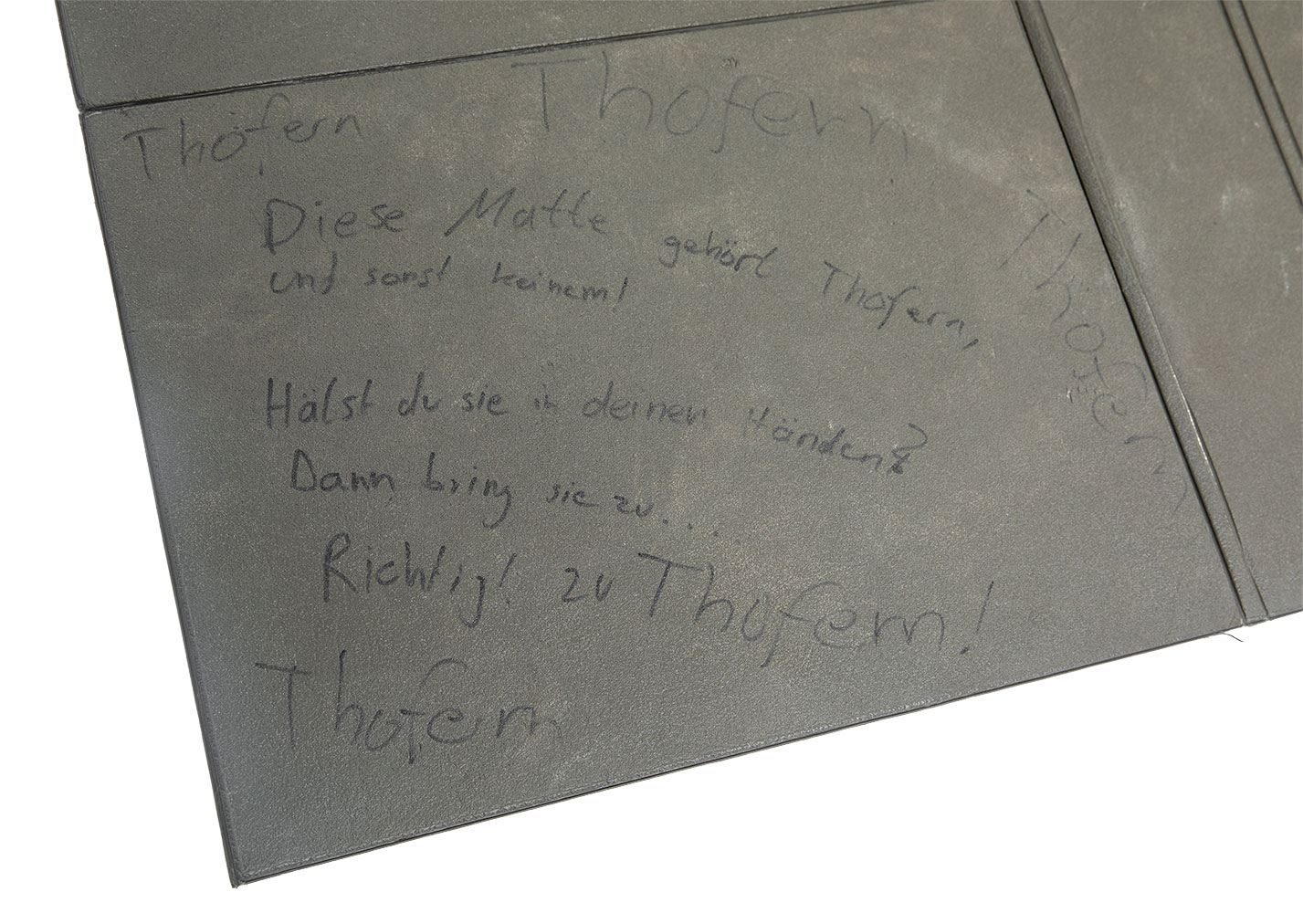 A close-up of the corner of the mat with the text in German as translated to English below.