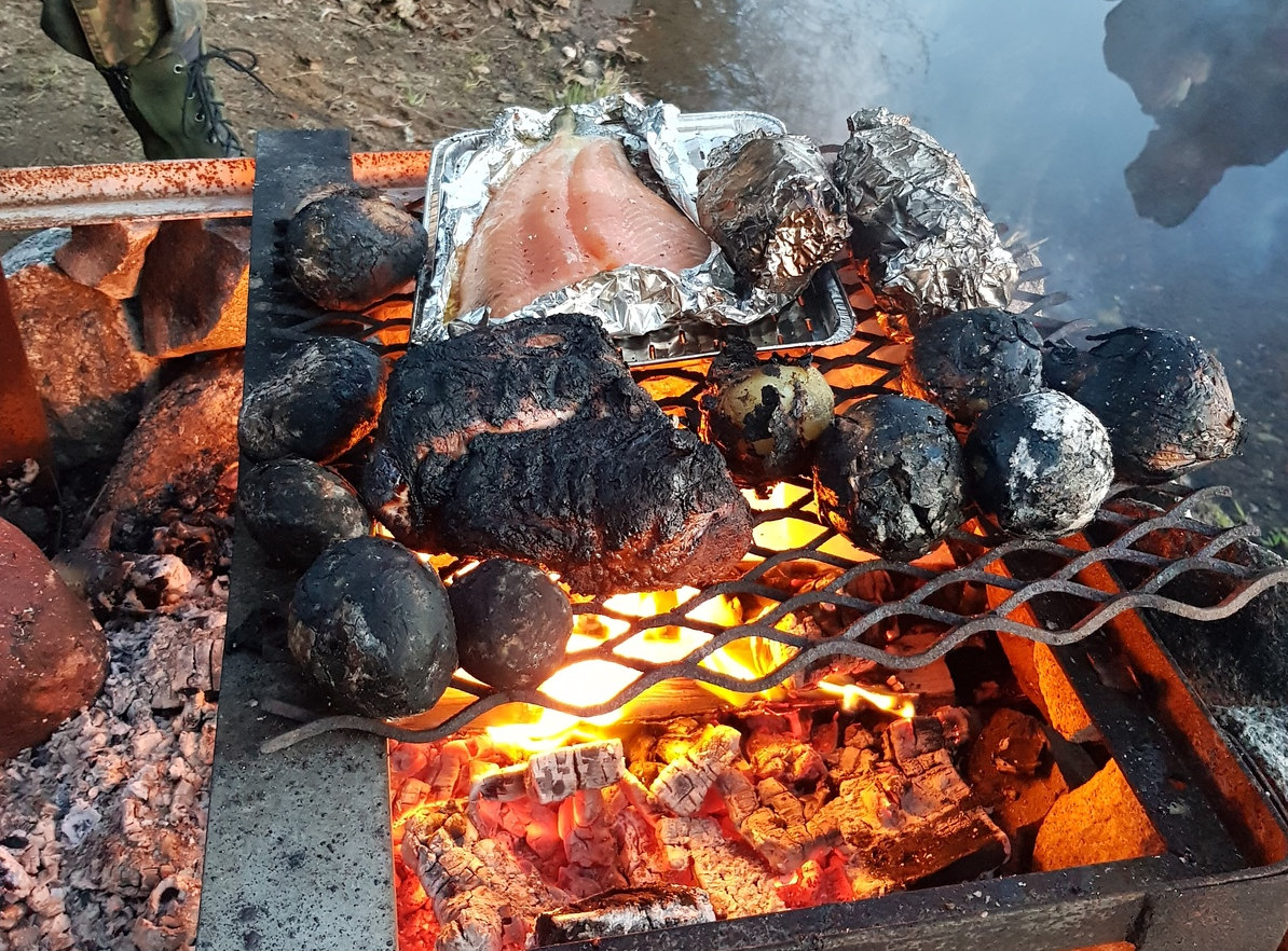 The charred foods on a griddle on the fire.