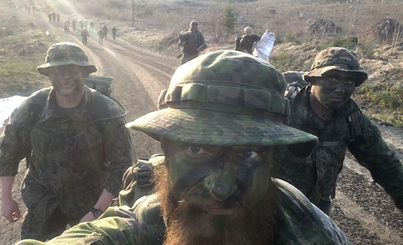 Sodiers on a dirt road wearing camoflauge clothing and face paint.