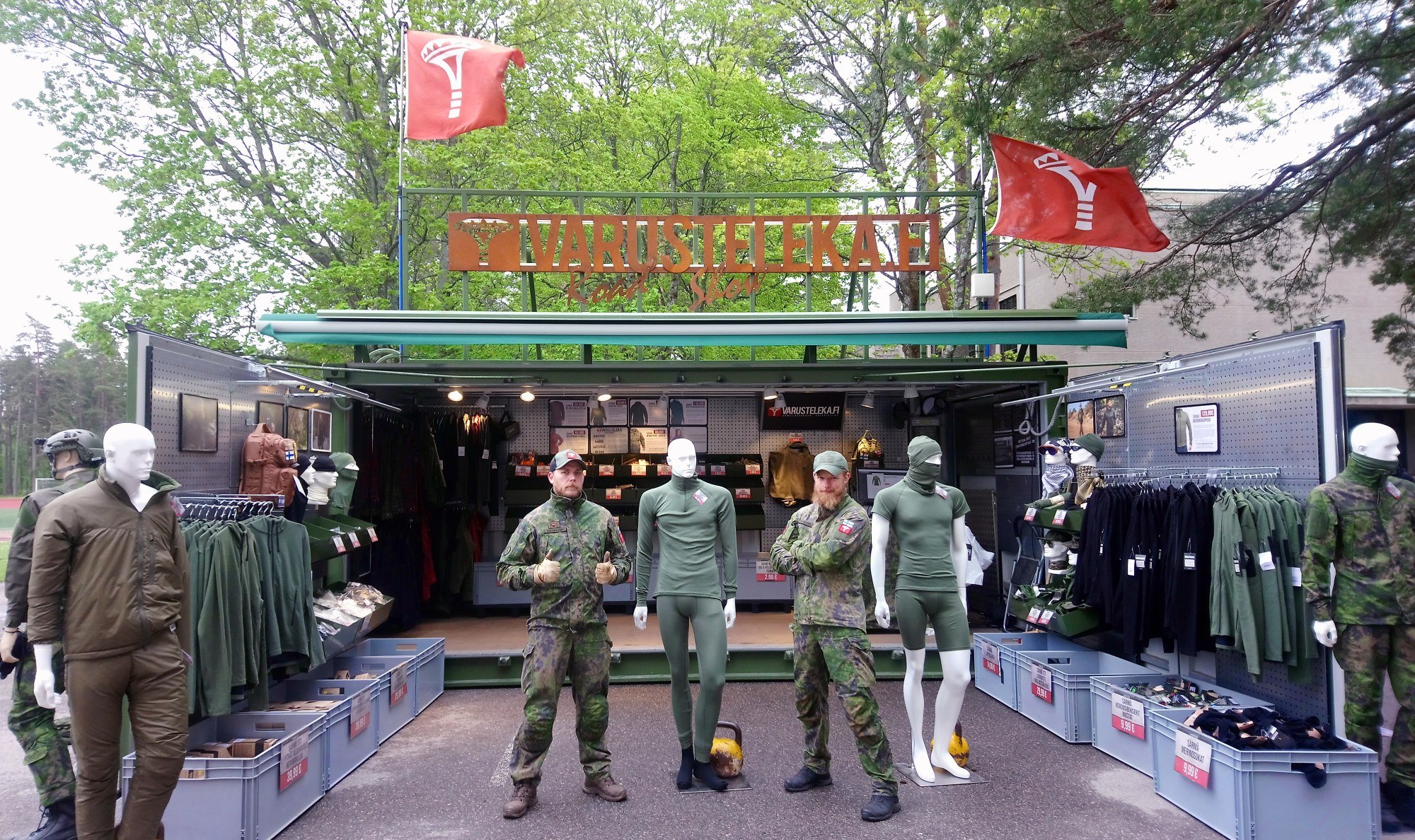 Two gentlemen wearing M05 camo clothing in front of Varusteleka container shop.