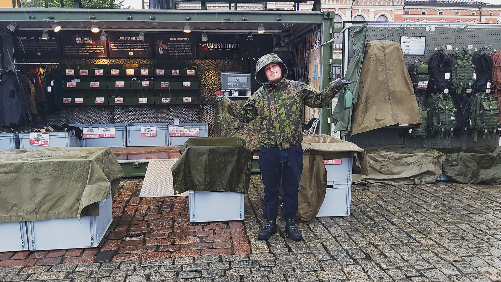 Man standing in the rain in front of Varusteleka's Container Shop