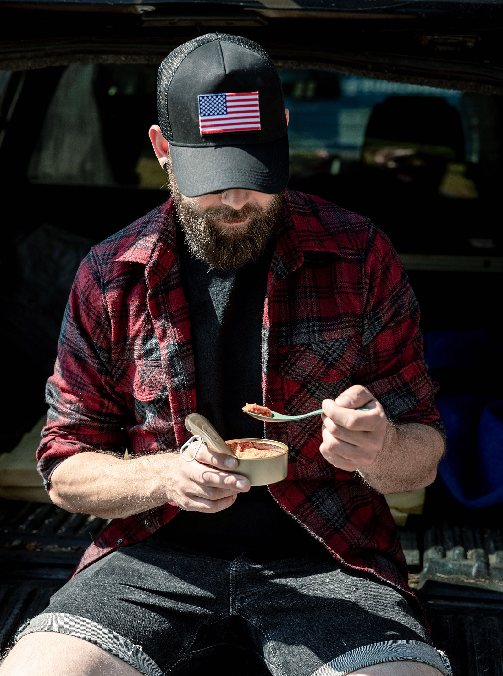 Man eating canned food in the back of the car