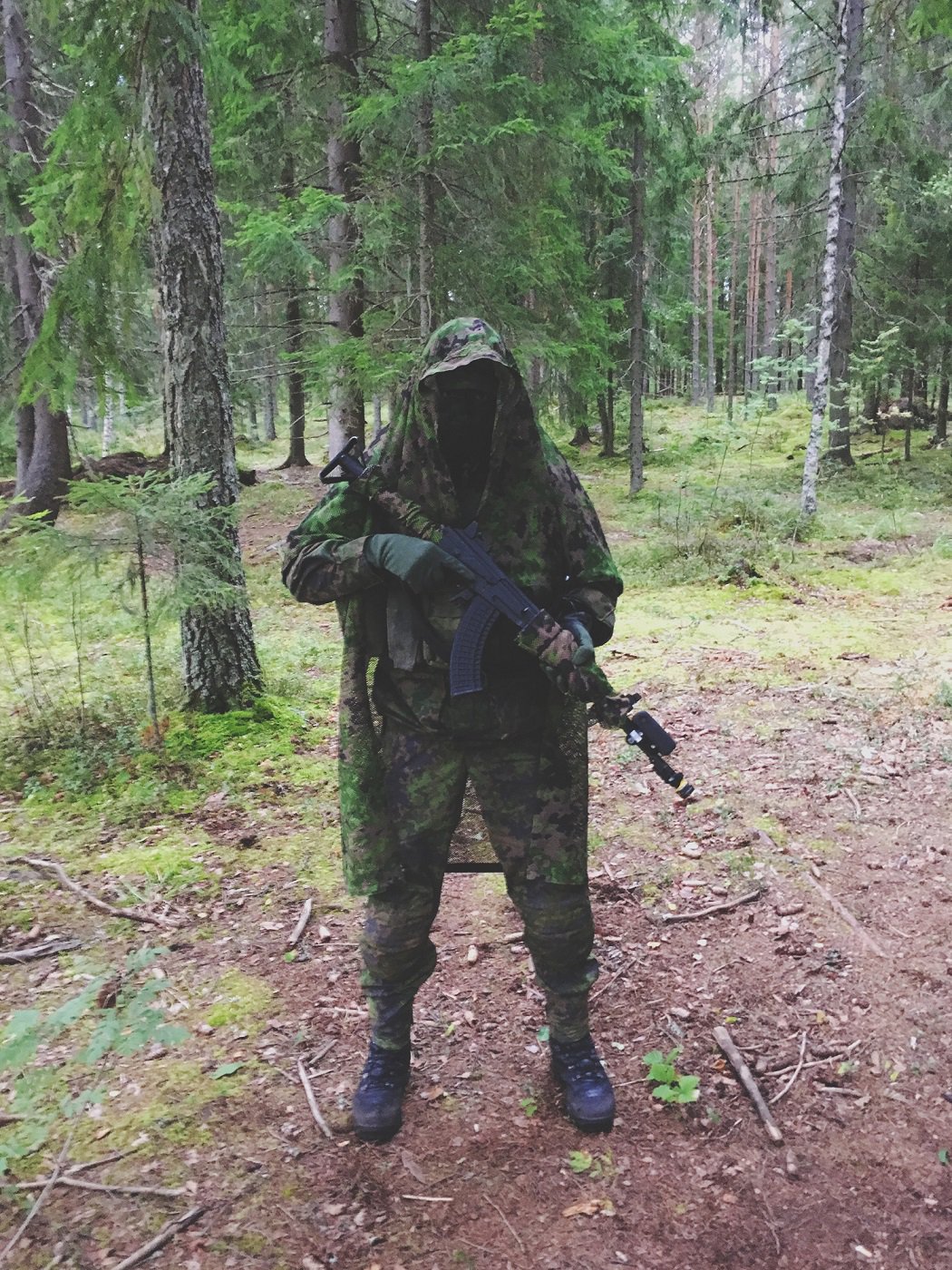 A soldier geared up in the woods.