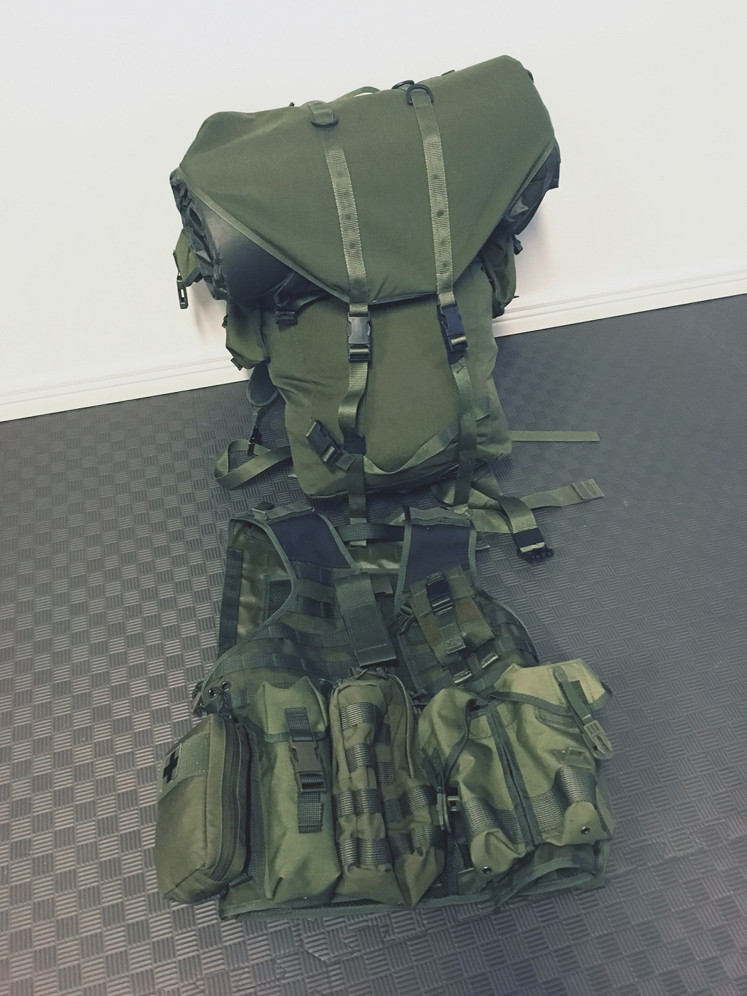 An army style green backpack and combat vest with pouches.