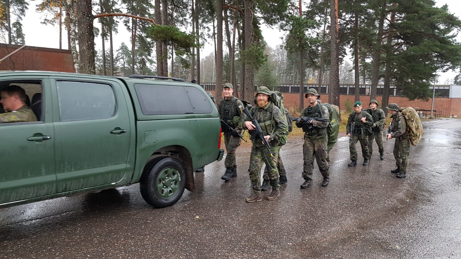 Soldiers marching after a pickup truck.