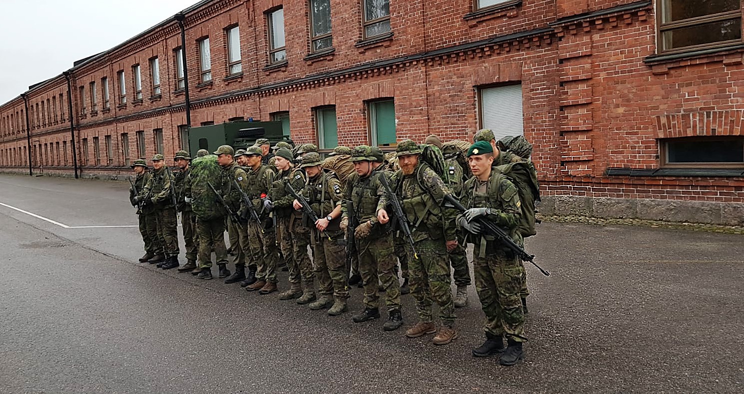 Parikymmentä sotilasta rivissä tiilirakennuksen edessä.