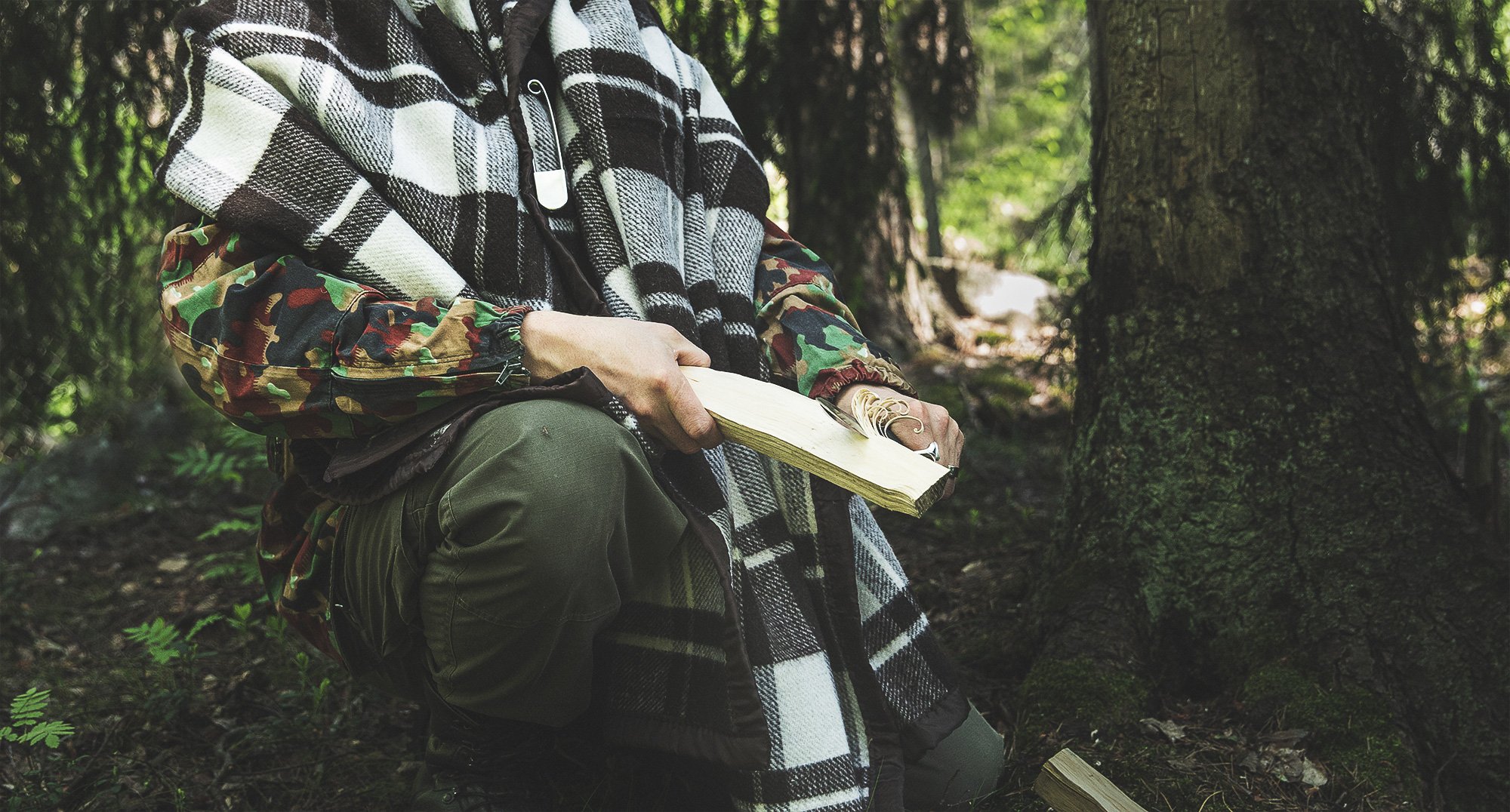 Man whittling a piece of wood with a Finnish puukko knife