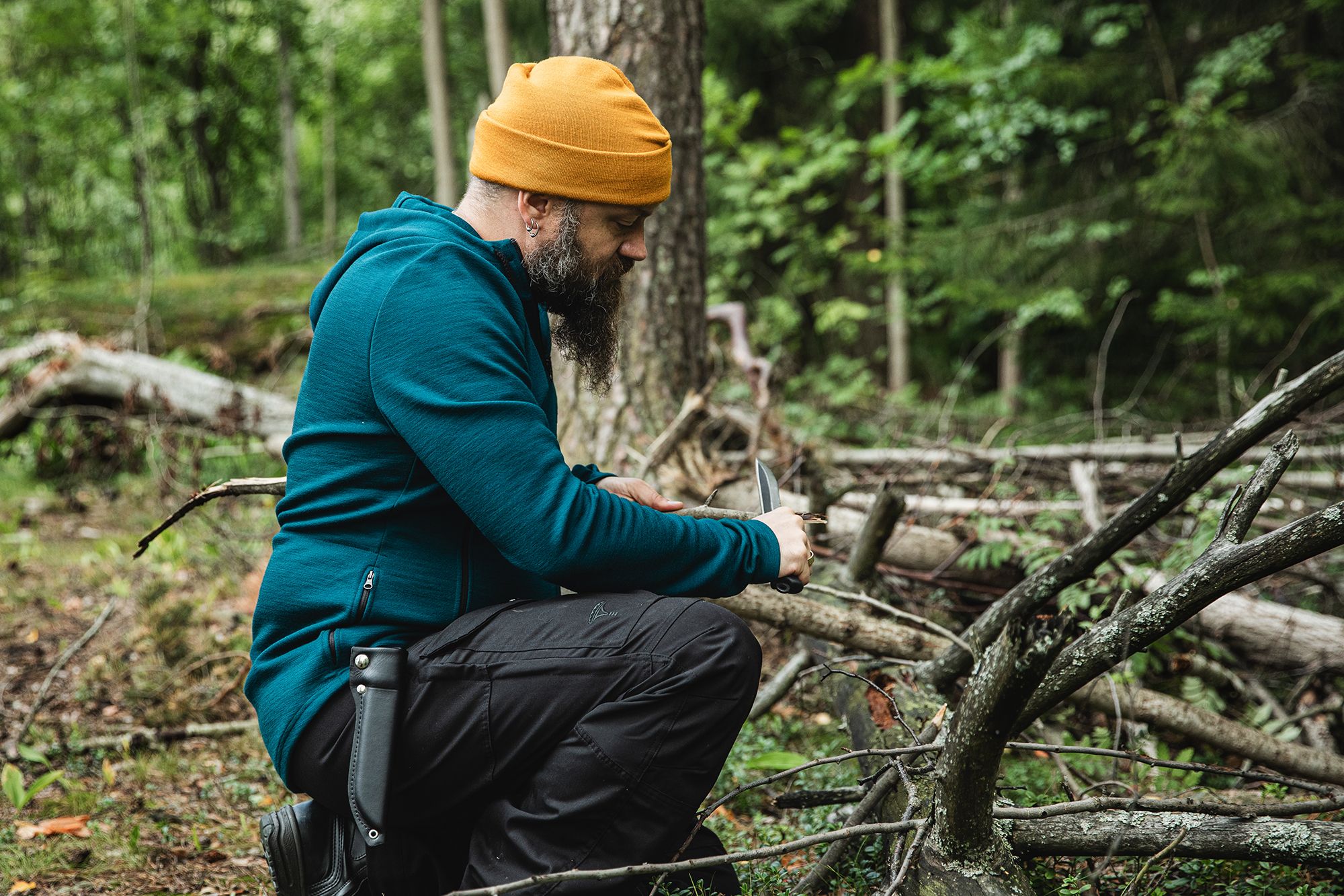 A man kneeling down and whittling.