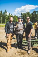 Three men standing on a field on a sunny day.