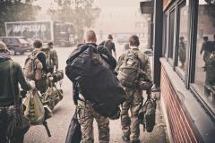 People on the airsoft training course carrying their gear at a parking lot.