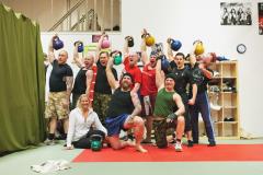 A spartan group of Varusteleka employees posing with kettle bells in the air.