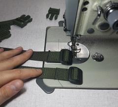 A sewing machine and the ends of two pieces of webbing with a Tri Glide buckle.