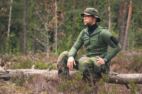 A man sitting in the woods with a merino hoodie on.