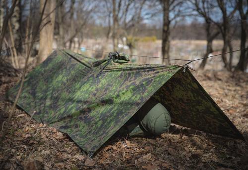 Särmä TST L6 Rain Poncho, M05 woodland camo. The poncho can be used to construct different types of emergency shelters.