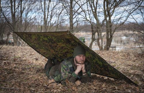Särmä TST Rain poncho, M05 woodland camo. The poncho can be used to construct different types of emergency shelters.