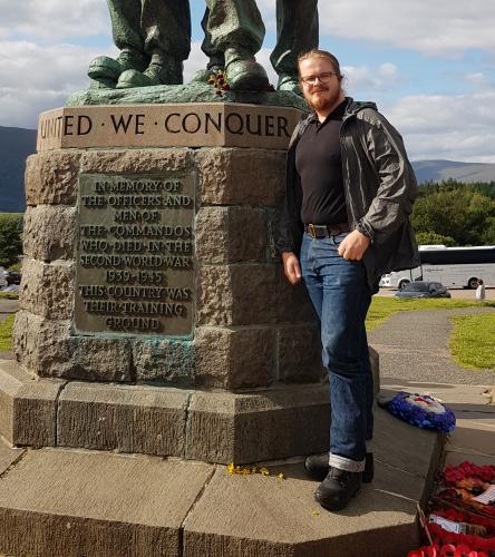 The long-haired man standing next to the statue.