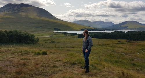 The long haired man gazing at the green rolling landscape.