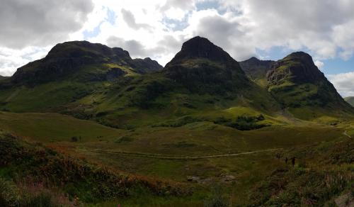 Rugged hills and grassy greens with a pathway going across it.