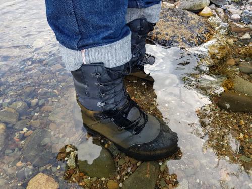 Feet with shoes standing in clear water.