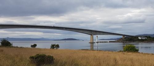 A tall and long bridge crossing a watrer.